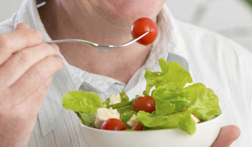 Happy mature man eating salad