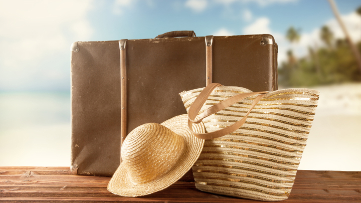 Old suitcase with accessories on beach what to pack for a cruise