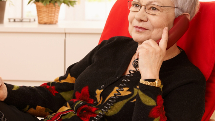 Pensioner woman using landline phone