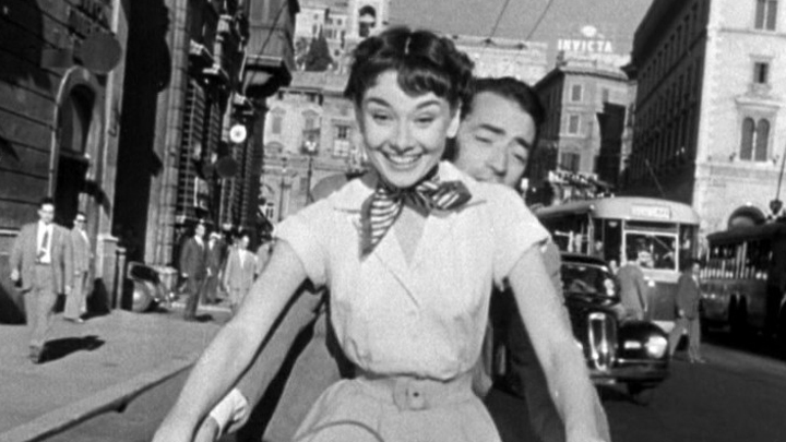 Audrey_Hepburn_and_Gregory_Peck_on_Vespa_in_Roman_Holiday_trailer