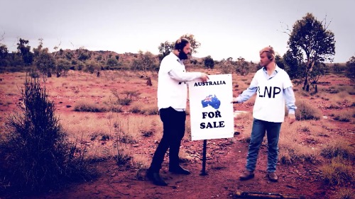 Two men wearing ALP and LNP t-shits hammer in a Australia for sale sign. 