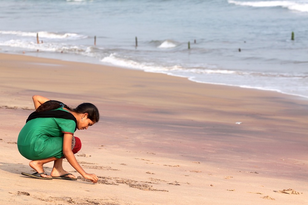 A woman writes in the sand 