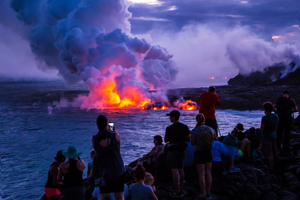 Tourists watch as the lava spills into the sea in the Volcanos National Park