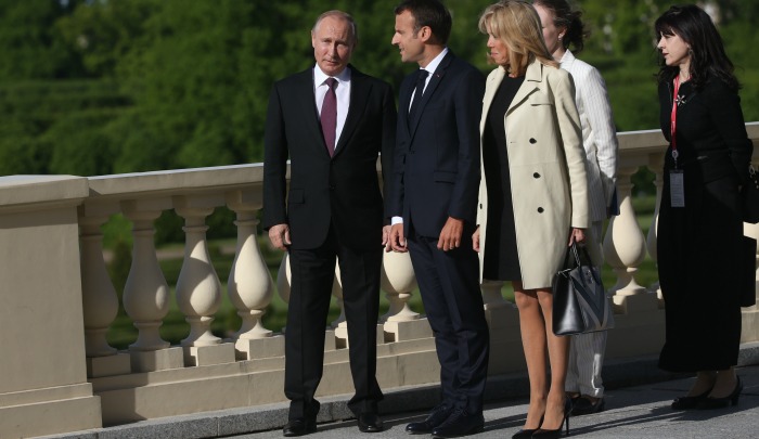 Brigitte Macron looks stylish in a classic trench coat with interesting button detail, as she and husband Emmanuel chat with Vladimir Putin (far left) on May 24. Source: Getty