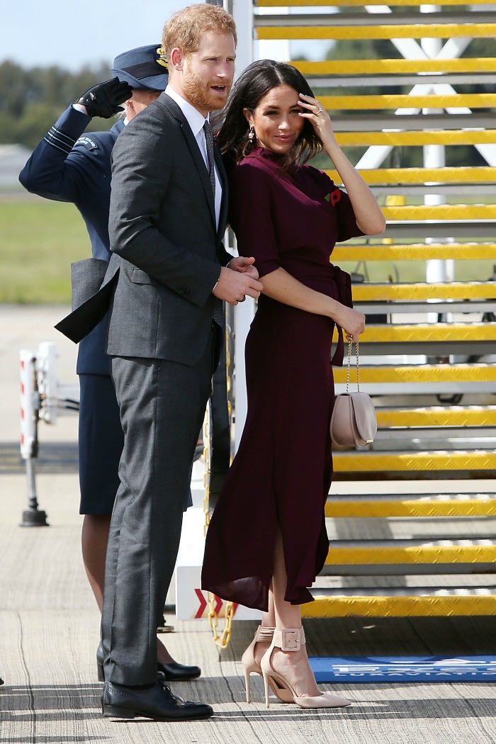 Meghan boarded the plane in a burgundy dress. Source: Getty.